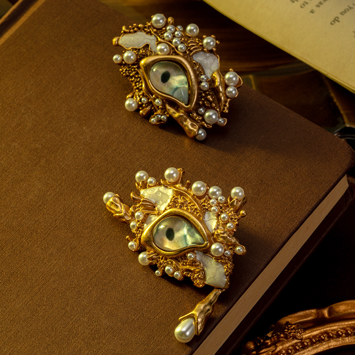Ornate baroque‑style eye motif Earrings crafted in antique gold tone, decorated with layered faux pearls. Unique retro statement brooch for coats, blazers and special‑occasion outfits.